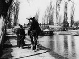 In den 1930er Jahren: Ein Mann neben einem Treidelpferd und  ein Lastkahn im Hintergrund.